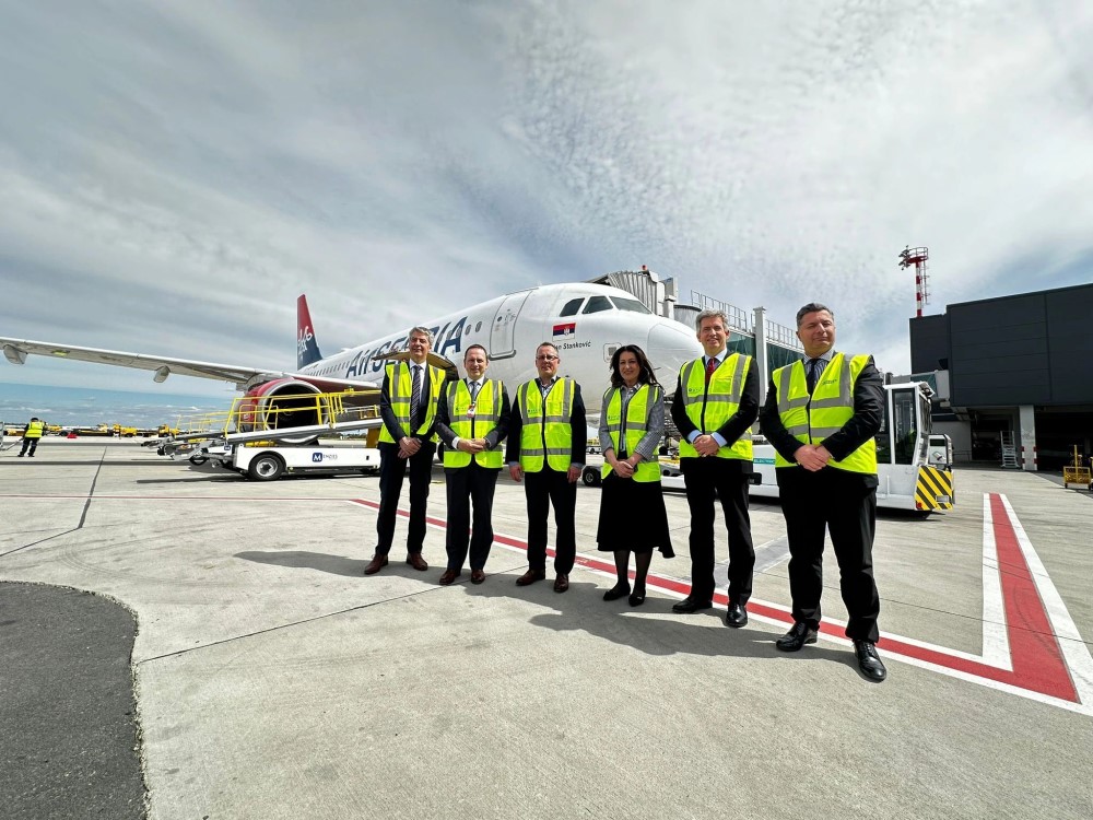 A group of Menzies employees standing in front of a plane