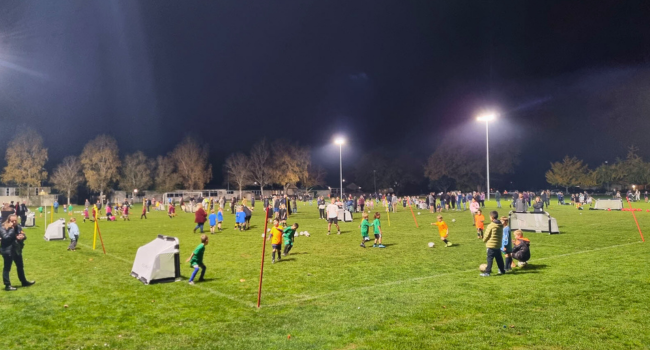 Children playing evening football beneath the floodlights