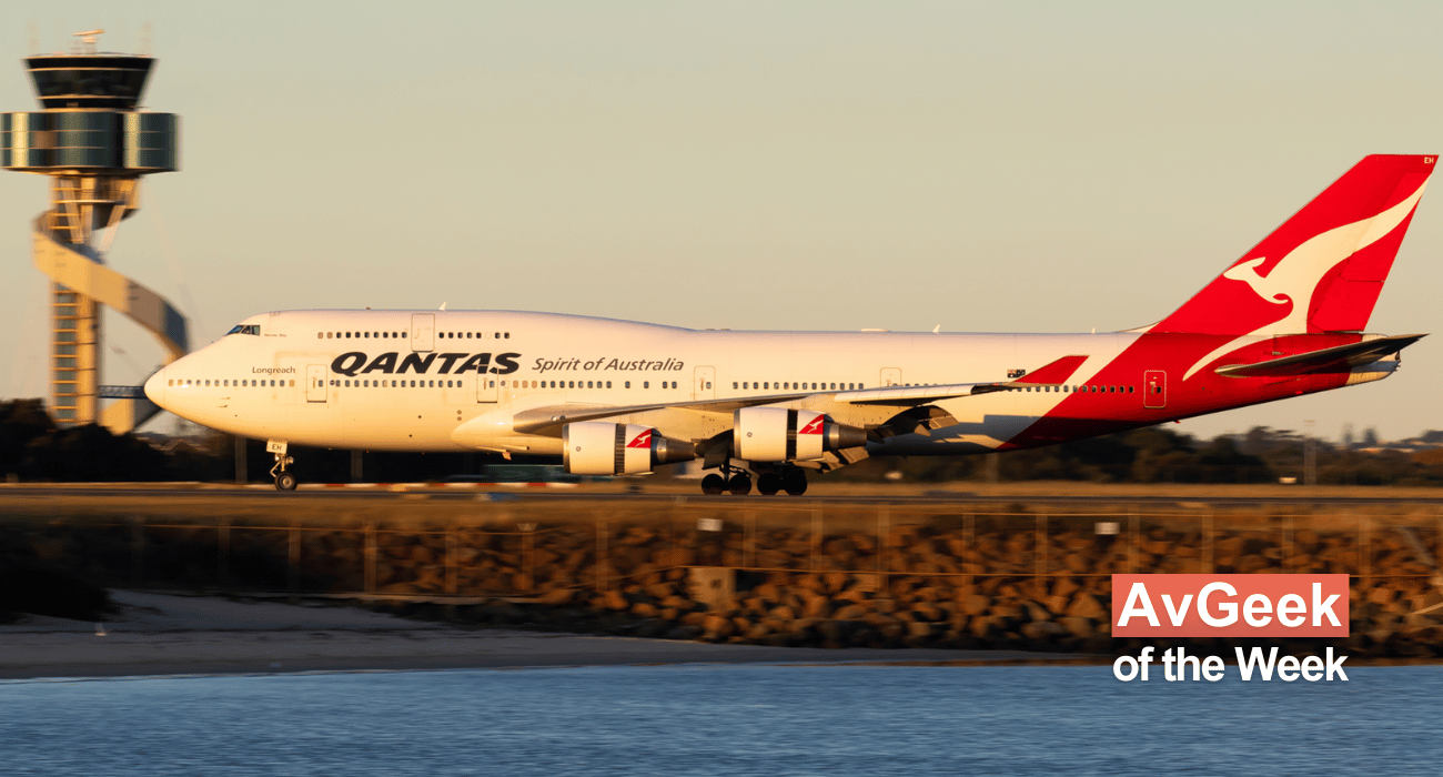 A Qantas 747 lands at a sunny Sydney Airport, the airports unique control tower is visible in the background